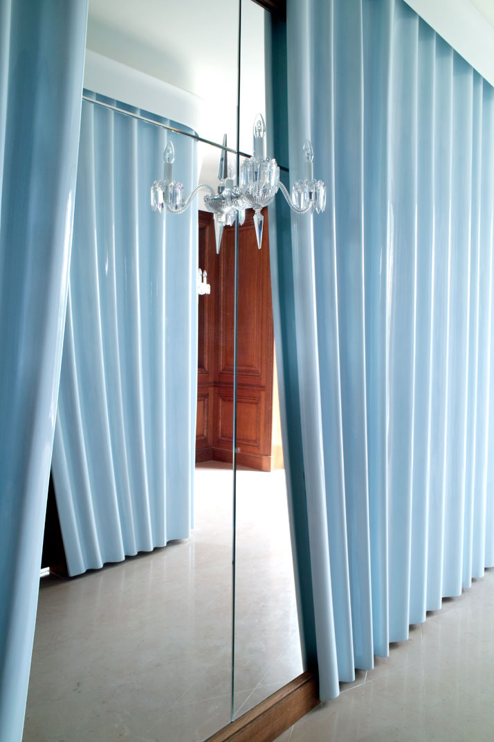 Curtains made of lacquered plaster cover the walls of the main entrance; the curtains’ pleats were hand-drawn by Fischler and then molded by an expert team of artisans. The painted mirror on the wall conceals a coat closet.Photo © Paul Graves for AD Magazine.