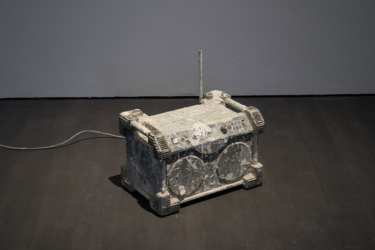 Installation view. Kris Martin, EXIT at S.M.A.K., Ghent, 2020. Photo by Dirk Pauwels.
Featured: Miserere, 2016. Radio, plaster, electronic units. König Galerie, Berlin/London/Tokyo.
Artist's statement: A robust radio from a building site, which typically blasts loud music, emits an almost inaudible version of Allegri’s Miserere."