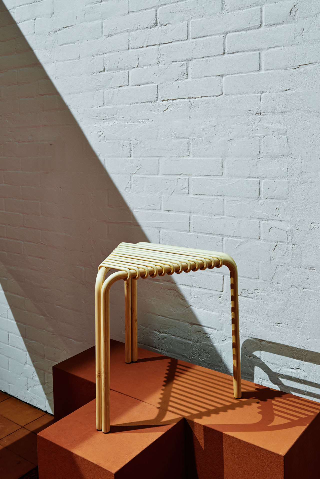 TRIANGULAR STOOL designed by Alvaro Siza for HERMÈS. (bamboo, L 40 × P 40 × H 40 cm W153/4 ×D153/4 ×H153/4in.)Photo by François Lacour inside La Pelota where Hermès presented its new Home collection.