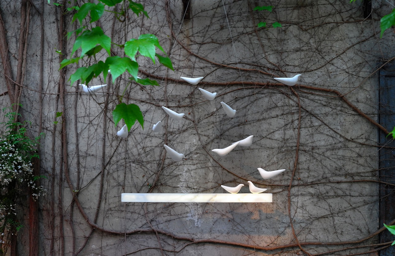 ‘Ray’ installation by on•entropy at the courtyard of Galleria Rossana Orlandi ; a pendant light which attracts a flock of marble birds. Photo by Tati Uzlova.