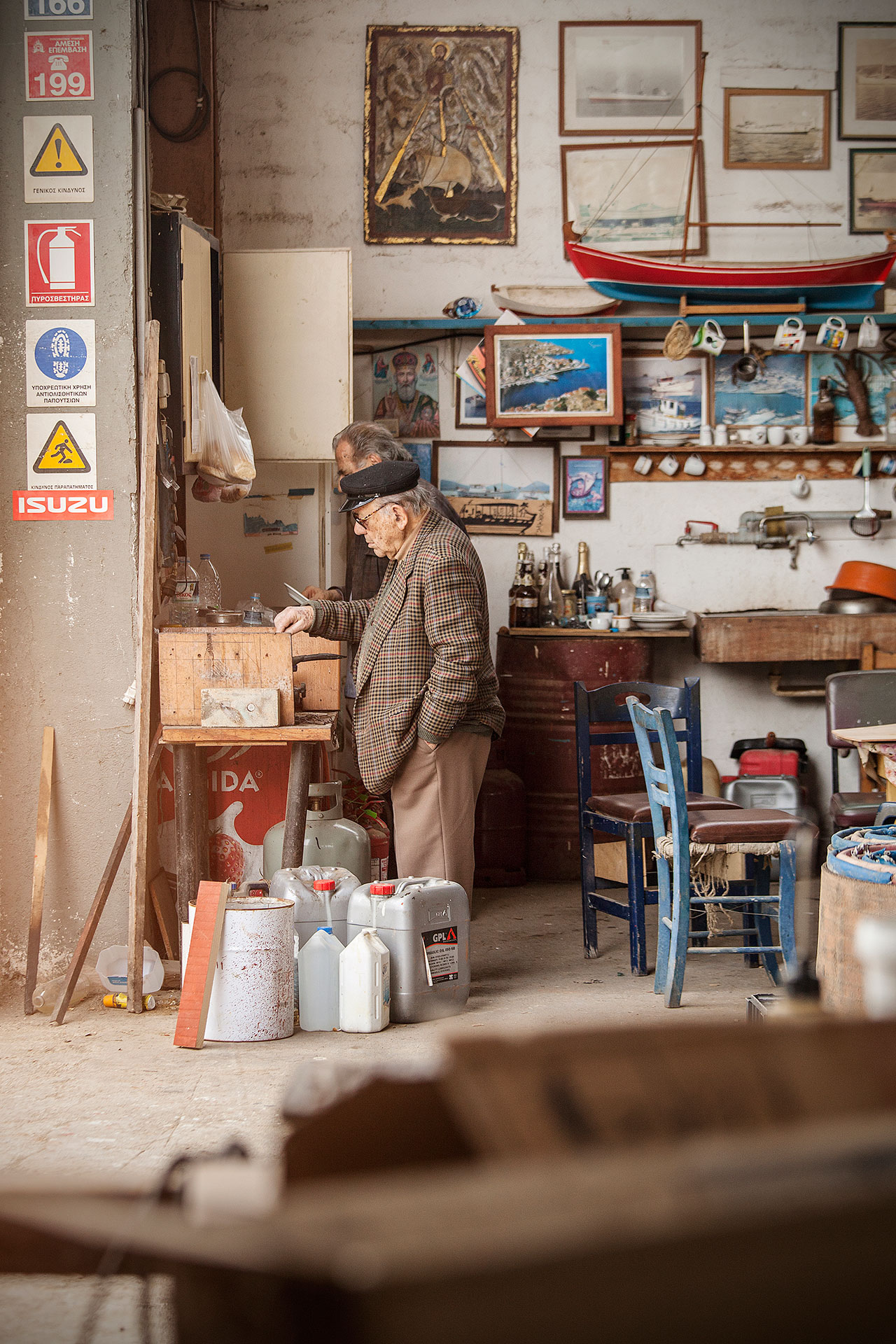 A shipyard of Kilada. One of the men stands by the gas stove and fries freshly caught sardines in olive oil. © Benjamin Tafel.